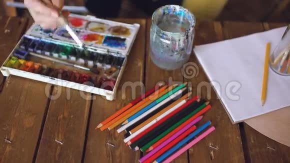 年轻的女画家用水彩画和画笔混合色彩来画图画视频的预览图