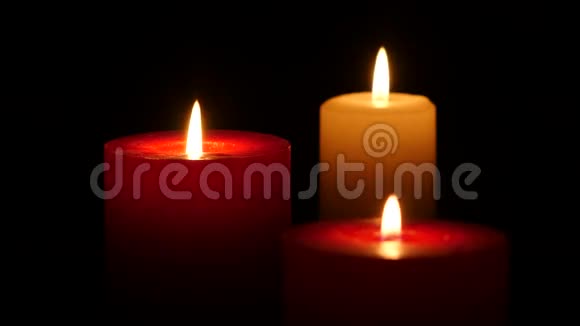 三支蜡烛在黑色背景上燃烧关闭视频的预览图