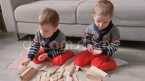 双胞胎兄弟正在用坐在他们房间沙发旁的木头积木搭建视频的预览图