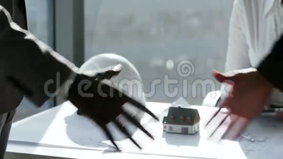 两位商业伙伴在大型全景窗口前见面时握手在慢动作中视频的预览图
