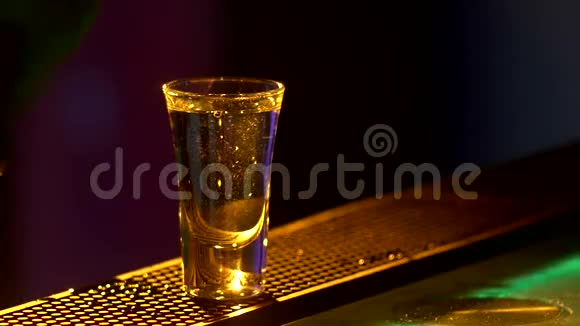 酒保正在制作鸡尾酒并加入三种不同的液体在酒吧柜台的边缘镜头背光缓慢视频的预览图
