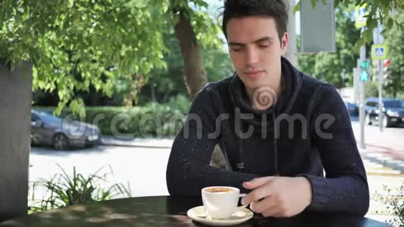 年轻人一边喝咖啡一边坐在咖啡厅露台上视频的预览图