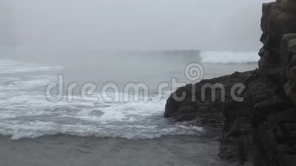 海滩雾笼罩着岩石和海浪视频的预览图