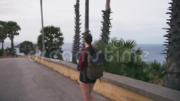 女旅行者欣赏海景用智能手机在海滩上拍照视频的预览图