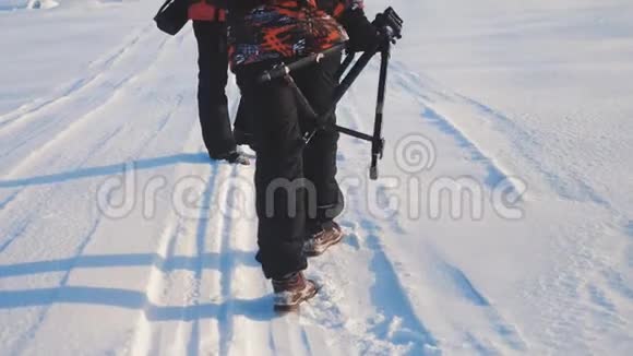 团队合作男游客摄影师在冬天乘三脚架爬山顶山顶岩峰群去雪视频的预览图