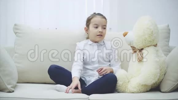快乐的小女孩坐在沙发上抱着一个大泰迪熊视频的预览图