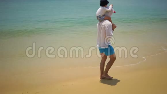 父子俩步行沿着靠近海洋的海滩散步视频的预览图