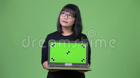美丽的亚洲女商人一边思考一边展示笔记本电脑视频的预览图