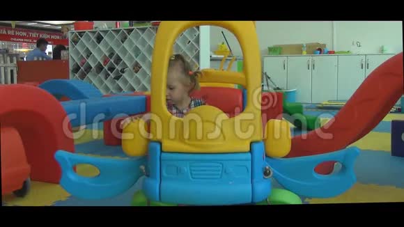 游戏室里的小漂亮女孩坐在玩具车里视频的预览图