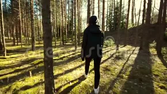 年轻的女性在森林中的树木中行走视频的预览图