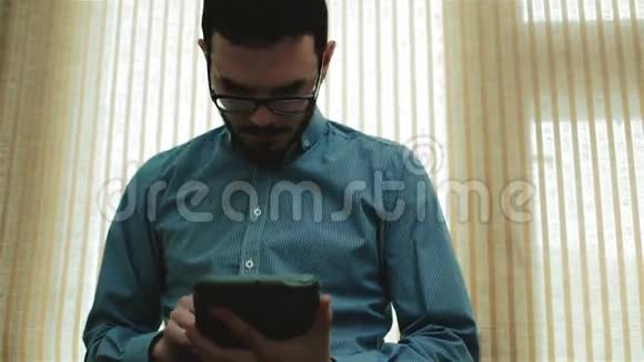 一个戴眼镜的年轻商人用平板电脑视频的预览图