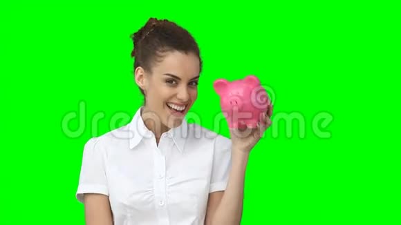 一个女人微笑着举起储蓄罐和一把现金视频的预览图
