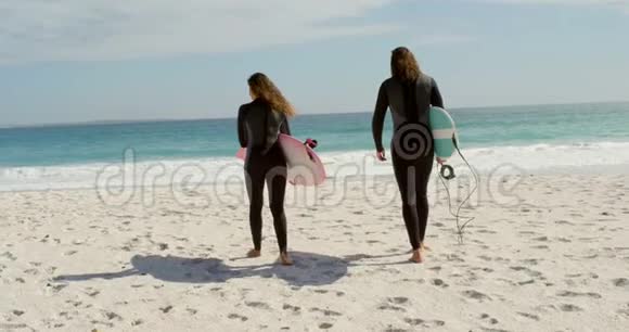 带着冲浪板在海滩散步的情侣视频的预览图