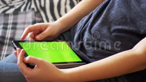 女孩躺在床上在家里使用带有绿色屏幕的平板电脑视频的预览图
