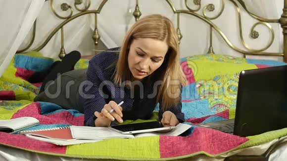 友好的女学生躺在床上看数字平板电脑美丽的女人在家里在线教育视频的预览图