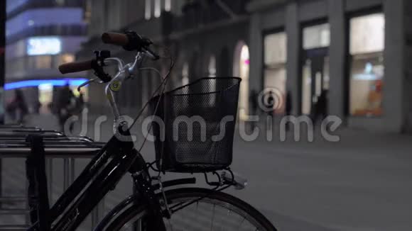 一个骑自行车的人带着包括手电筒在内的手电筒穿过城市带篮子的自行车视频的预览图
