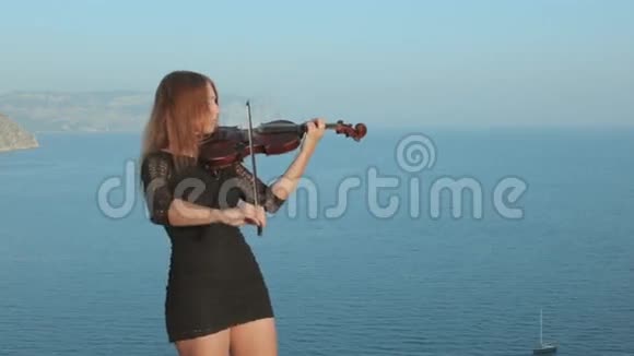 穿短裙的女孩站在海边的岩石上视频的预览图