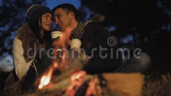 浪漫的情侣在篝火旁休息微笑亲吻和爱抚视频的预览图