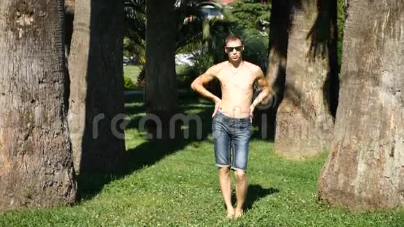一个年轻快乐的家伙赤裸的躯干在一个夏季公园里跳舞跳现代芭蕾舞慢分子视频的预览图