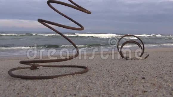 两个生锈的金属弹簧在沙滩和海浪上视频的预览图