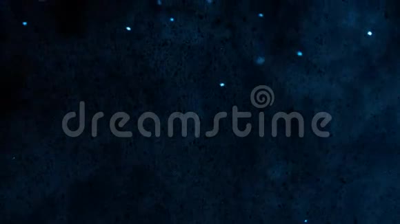 明亮而蓝色的粒子漂浮在烟雾朦胧的黑暗背景上视频的预览图