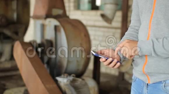 男性手拿着一部现代化的触摸屏手机和模糊的旧工厂图像视频的预览图