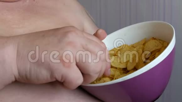 胖懒汉正坐在椅子上吃薯片男人的大肚子快餐不是健康食品视频的预览图