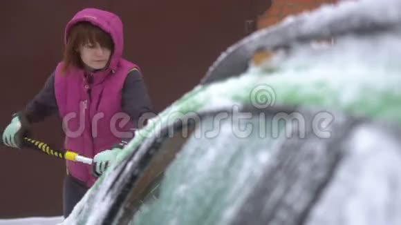 年轻女子在车上擦雪和冰冬季暴风雪视频的预览图
