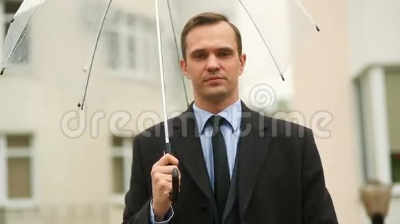 因天气而沮丧雨中站在伞下穿西装不开心的男人视频的预览图