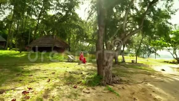 穿红衣服的美丽女子漫步热带花园视频的预览图