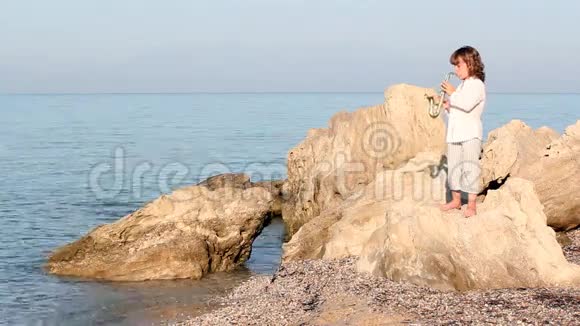 小女孩站在岩石上玩萨克斯管视频的预览图