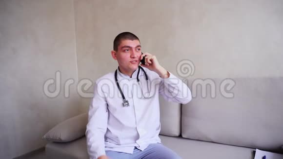 移动电话医生给坐在医院办公室沙发上的病人提供建议的画像视频的预览图