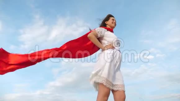 性感的超级英雄女孩穿着红色斗篷站在田野上斗篷在风中飘扬女孩梦想成为一个视频的预览图