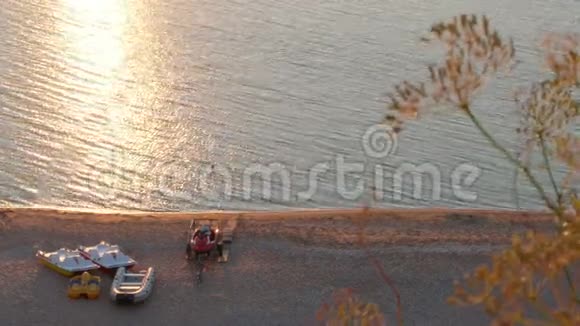 日落时海滩上的黄船海面上太阳耀斑视频的预览图