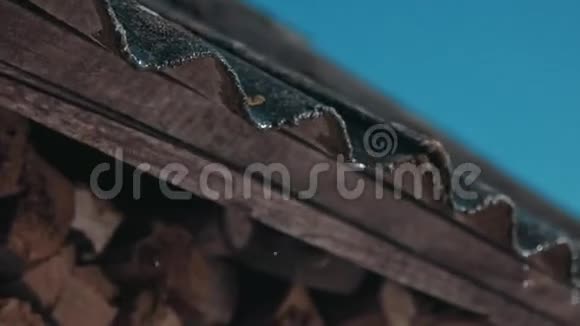 在一个阳光明媚的春天屋顶上的雪融化水滴从屋顶边缘落下视频的预览图