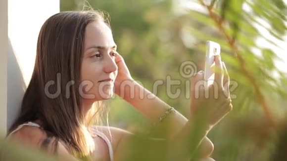 女人使用智能手机坐在露台上背景是花园视频的预览图