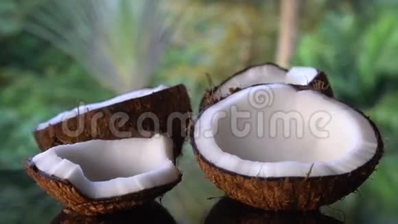 黑色玻璃桌上的椰子被隔离在模糊的棕榈树背景上视频的预览图