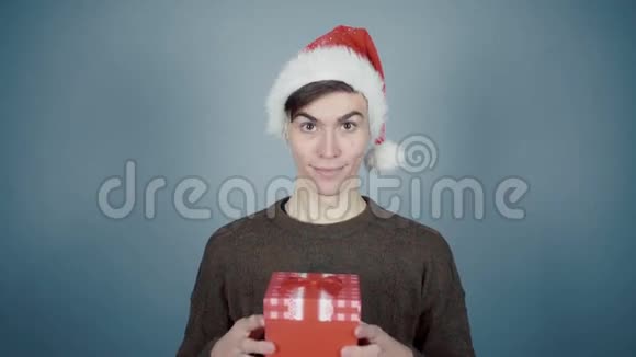 戴着圣诞帽的年轻人打开一个礼品盒里面有一个惊喜看到咖啡杯视频的预览图