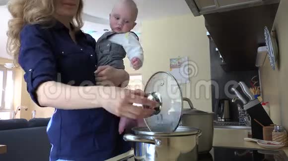 妈妈带着宝宝在手里做饭在锅里拌饭品尝4K视频的预览图