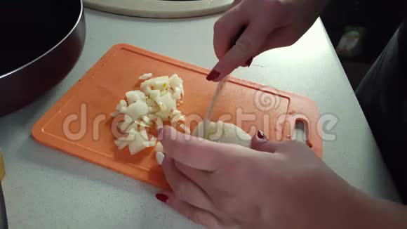 女人在厨板上切洋葱在家做饭视频的预览图