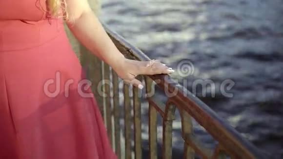 可爱的金发女郎穿着红色裙子走在堤岸上视频的预览图