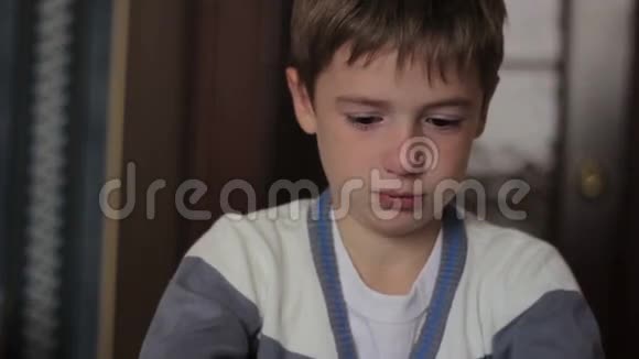 一个生病的男孩坐在桌子旁吹鼻涕视频的预览图
