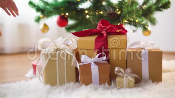 手拿圣诞树下的礼品盒视频的预览图