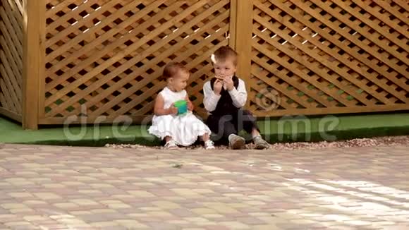 小男孩和小女孩坐在露台附近吃东西视频的预览图