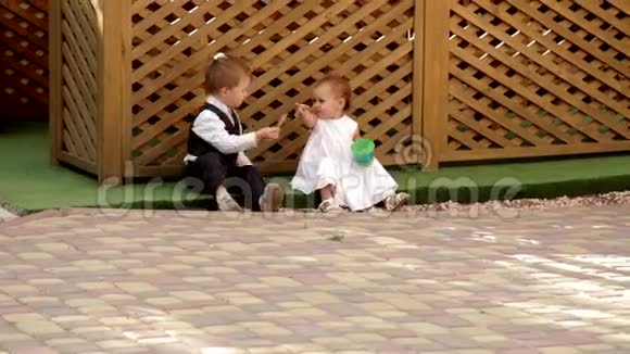 小男孩和小女孩坐在露台附近吃东西视频的预览图