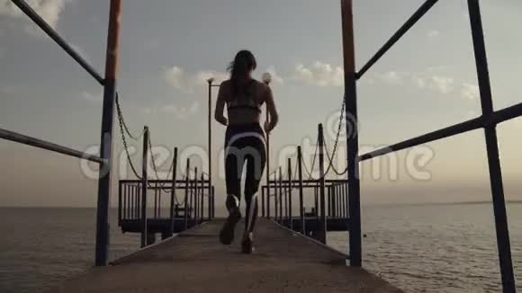 一位身材优美的女运动员在海边的码头上奔跑女运动员完成训练快乐地训练视频的预览图