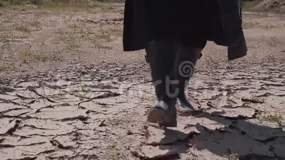 一个穿皮靴的人在开裂的地面上沙漠关门视频的预览图