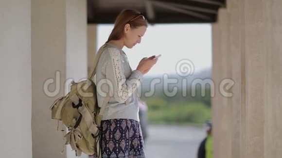 年轻漂亮的女游客在公共汽车站使用视频的预览图