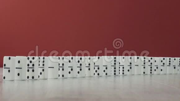多米诺效应一系列白色多米诺骨牌在红色背景上从链条上掉下来视频的预览图