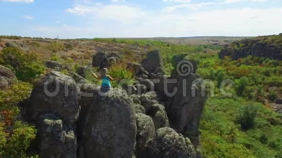 空中女人坐在岩石上的莲花位置视频的预览图